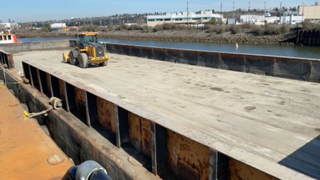 A piece of construction equipment on an empty barge.